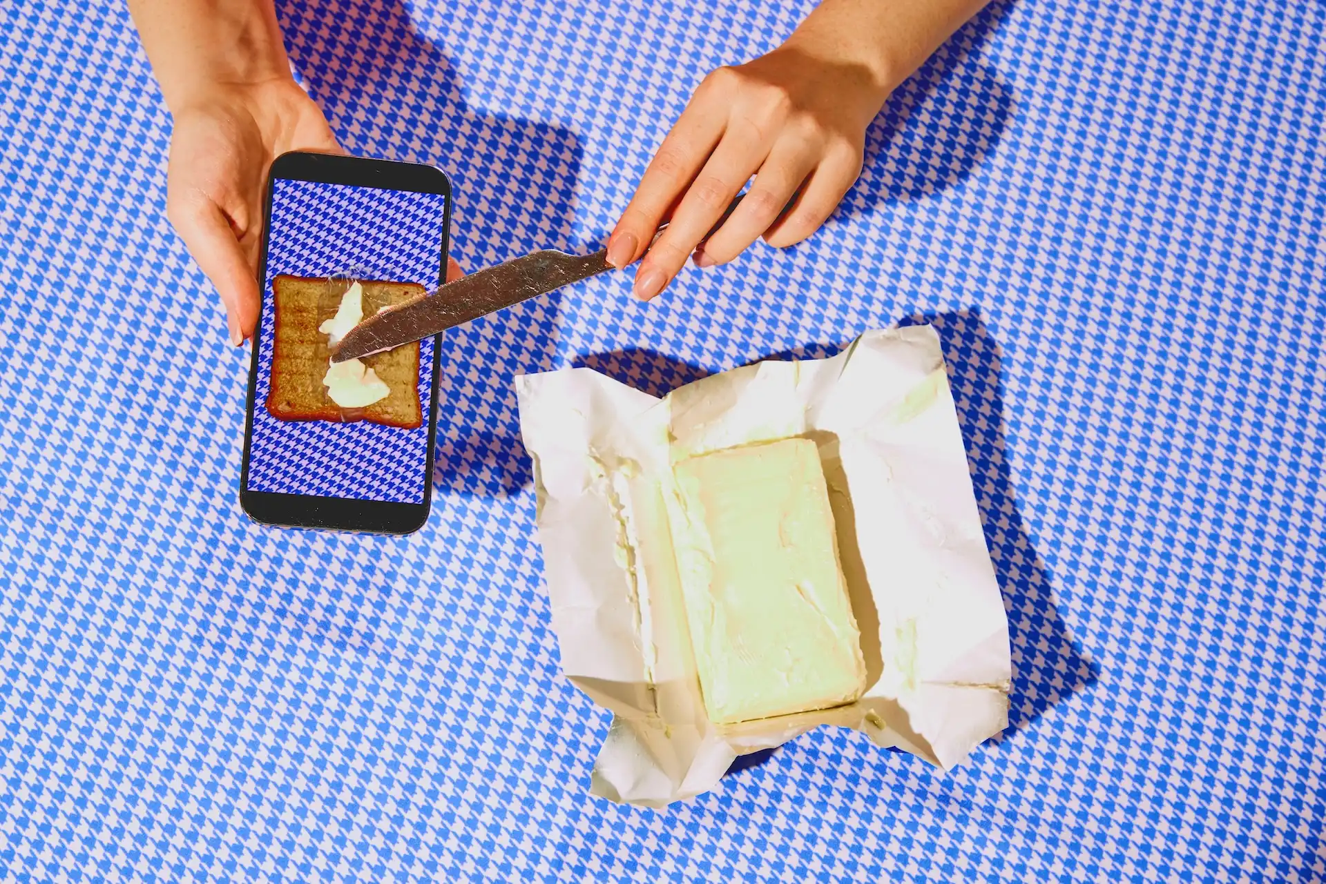 Hands buttering toast through an iPhone screen